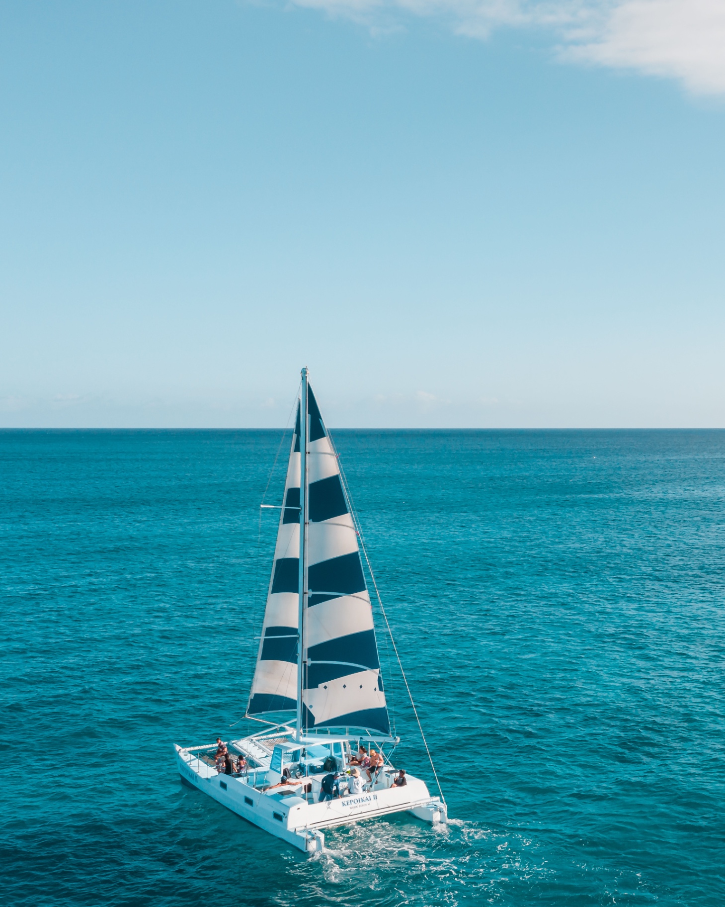 Catamaran sailing along a clear tropical coast